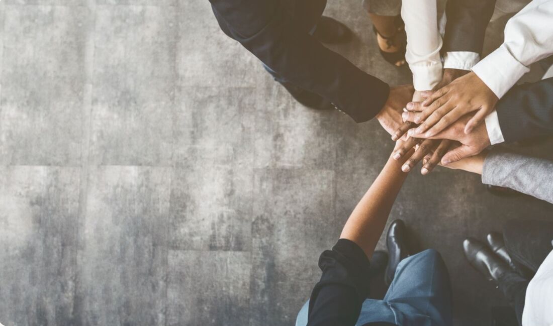 A team of colleagues placing their hands together in a circle